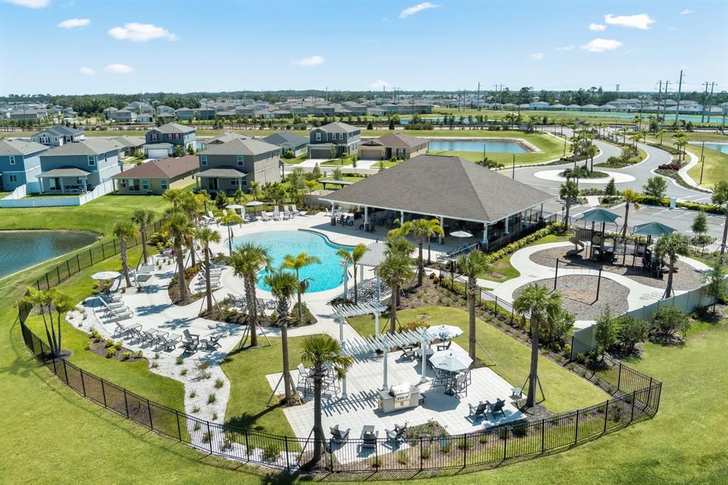 An aerial view shows a community swimming pool, playground, and clubhouse surrounded by residential homes — 9120 SANDY BLUFFS CIRCLE, PARRISH, FL