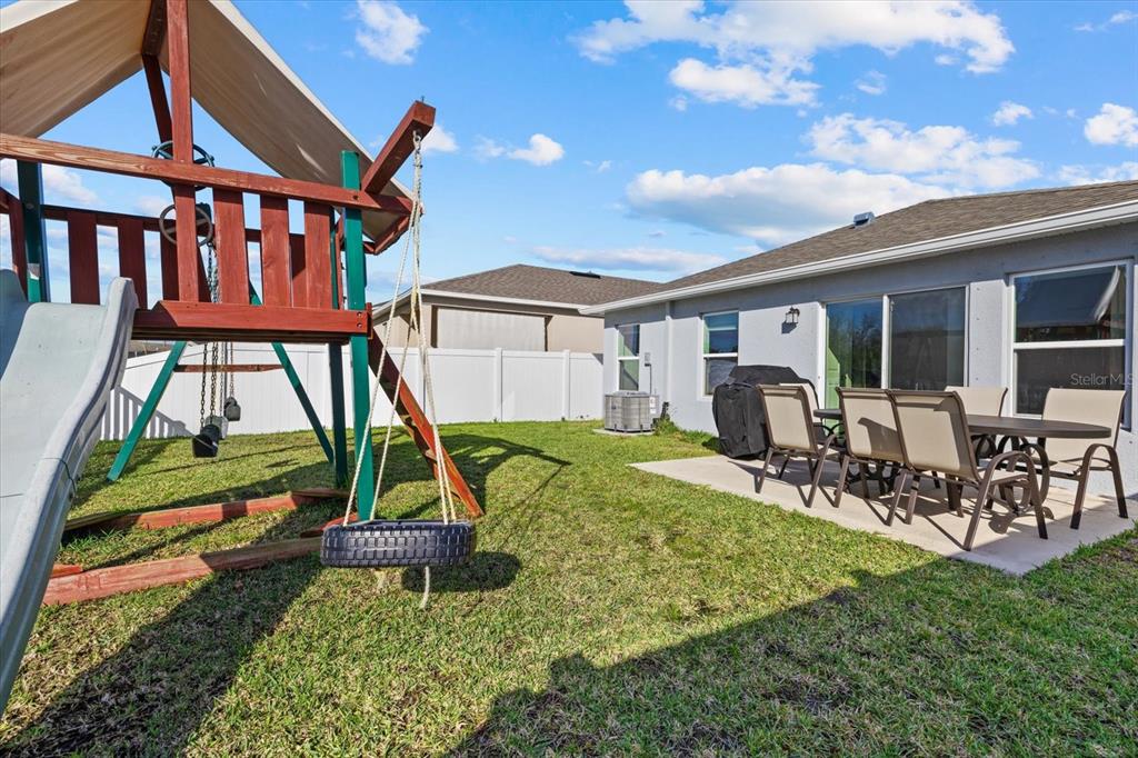 A backyard features a wooden playset with a slide and a patio with outdoor furniture — 9120 SANDY BLUFFS CIRCLE, PARRISH, FL