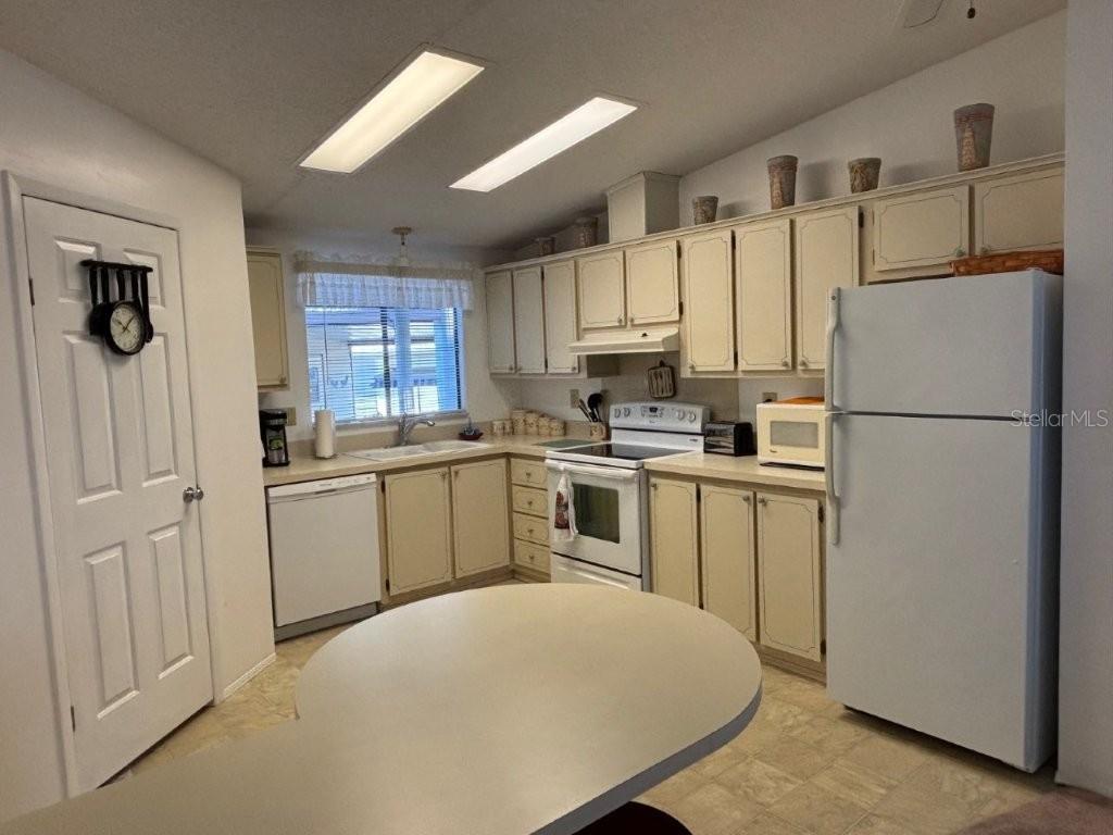 A kitchen features off-white cabinets, a white refrigerator, a dishwasher, and a central island — 617 WEBB WAY, LADY LAKE, FL