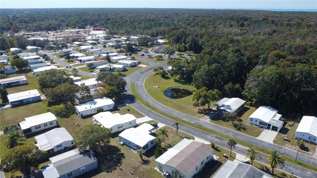 An aerial view shows a residential neighborhood of manufactured homes with a small central pond — 0 FOREST GLENN DRIVE, SPRING HILL, FL
