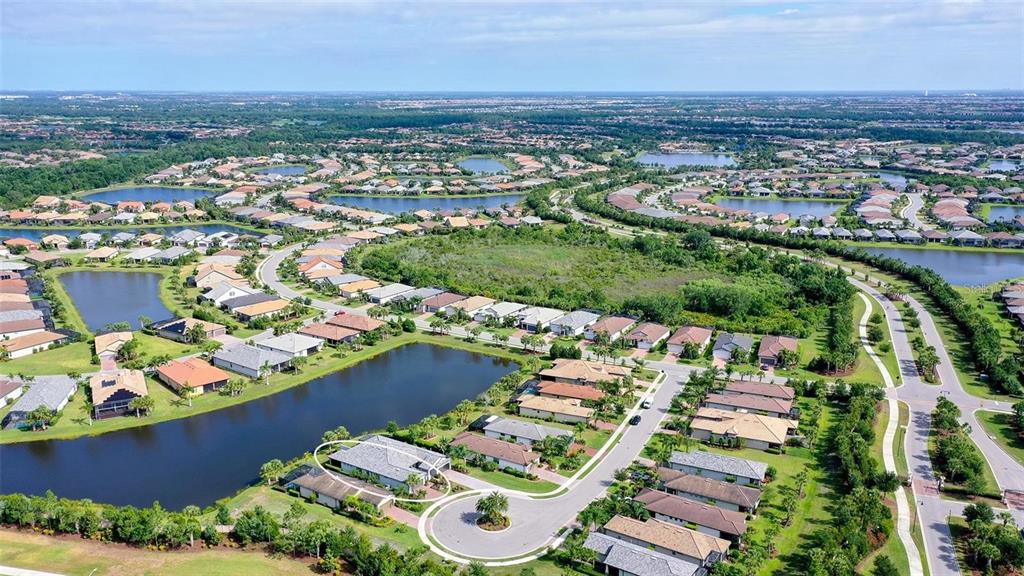 An aerial view shows a residential neighborhood with houses surrounding several ponds and green spaces — 7636 KIRKLAND COVE, LAKEWOOD RANCH, FL