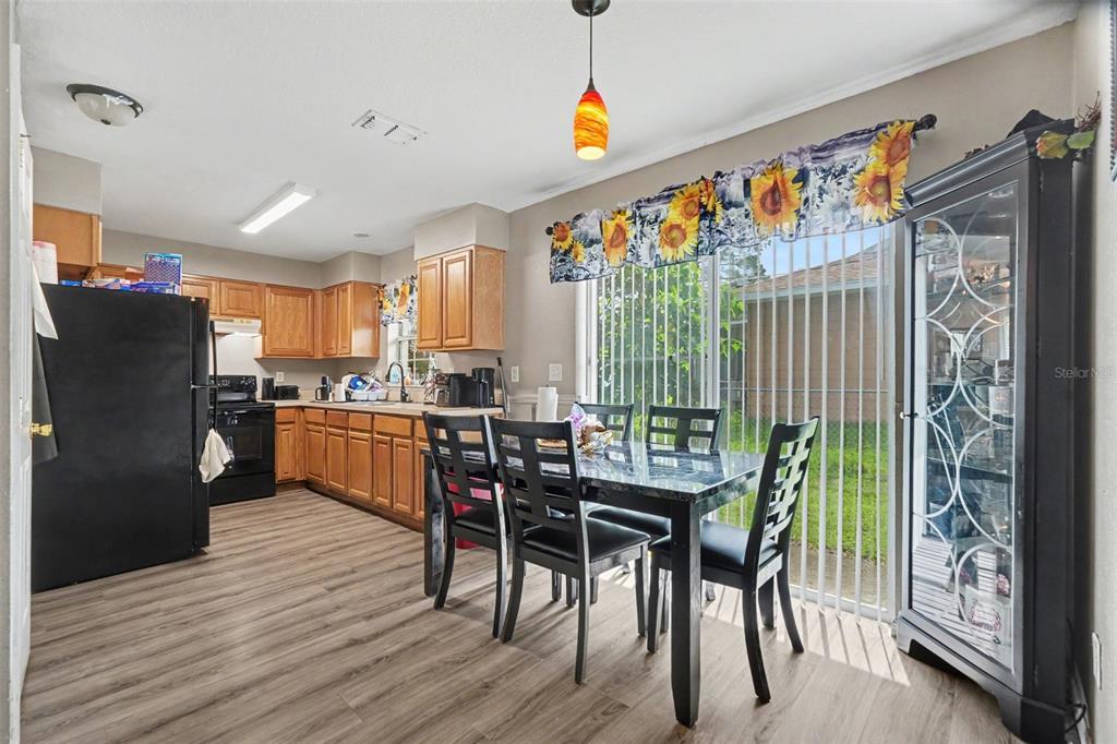 A kitchen and dining area with wood-look flooring, oak cabinets, black appliances, and a glass door — 38638 PATTI LANE, DADE CITY, FL