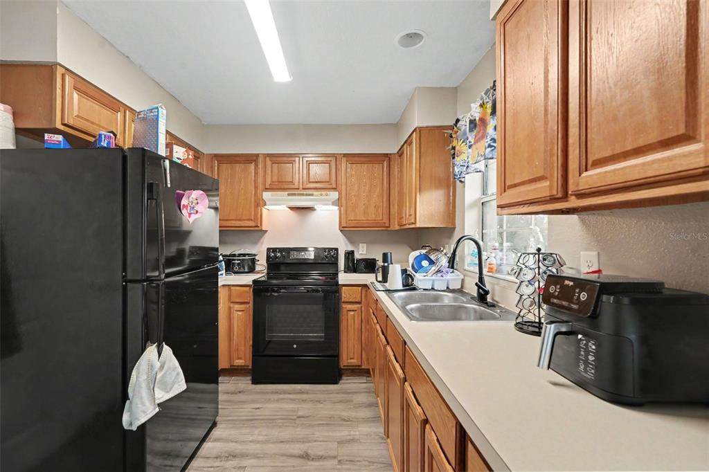 A kitchen features wood cabinets, black appliances, a double sink, and light-colored countertops — 38638 PATTI LANE, DADE CITY, FL