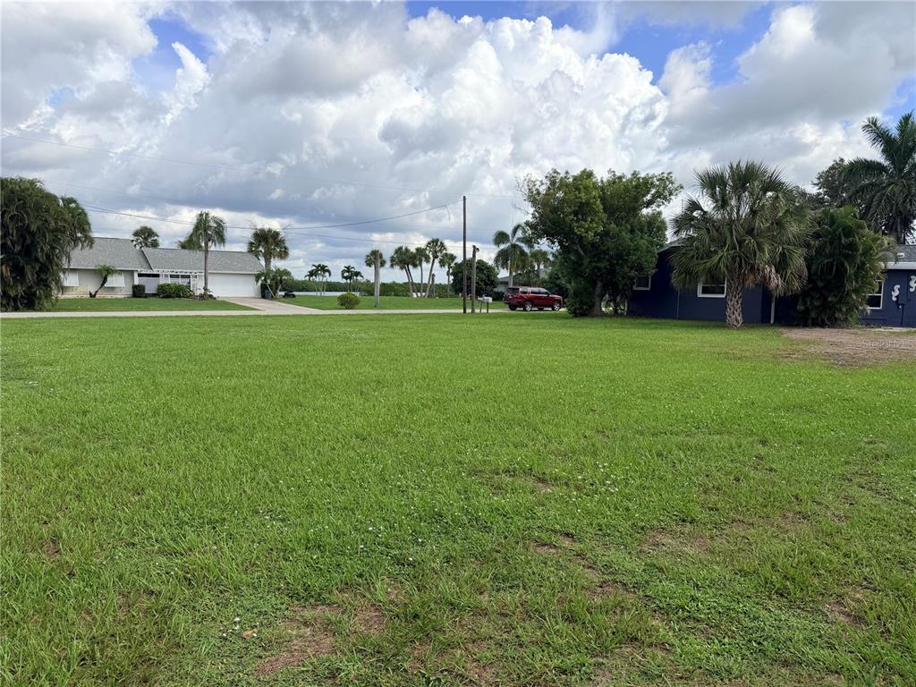 A large, grassy vacant lot sits in front of a residential street with palm trees — 2036 RIVER BASIN TERRACE, PUNTA GORDA, FL