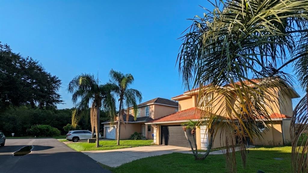 Two two-story stucco houses with tile roofs sit next to each other on a sunny day — 423 WATERFORD WAY, KISSIMMEE, FL