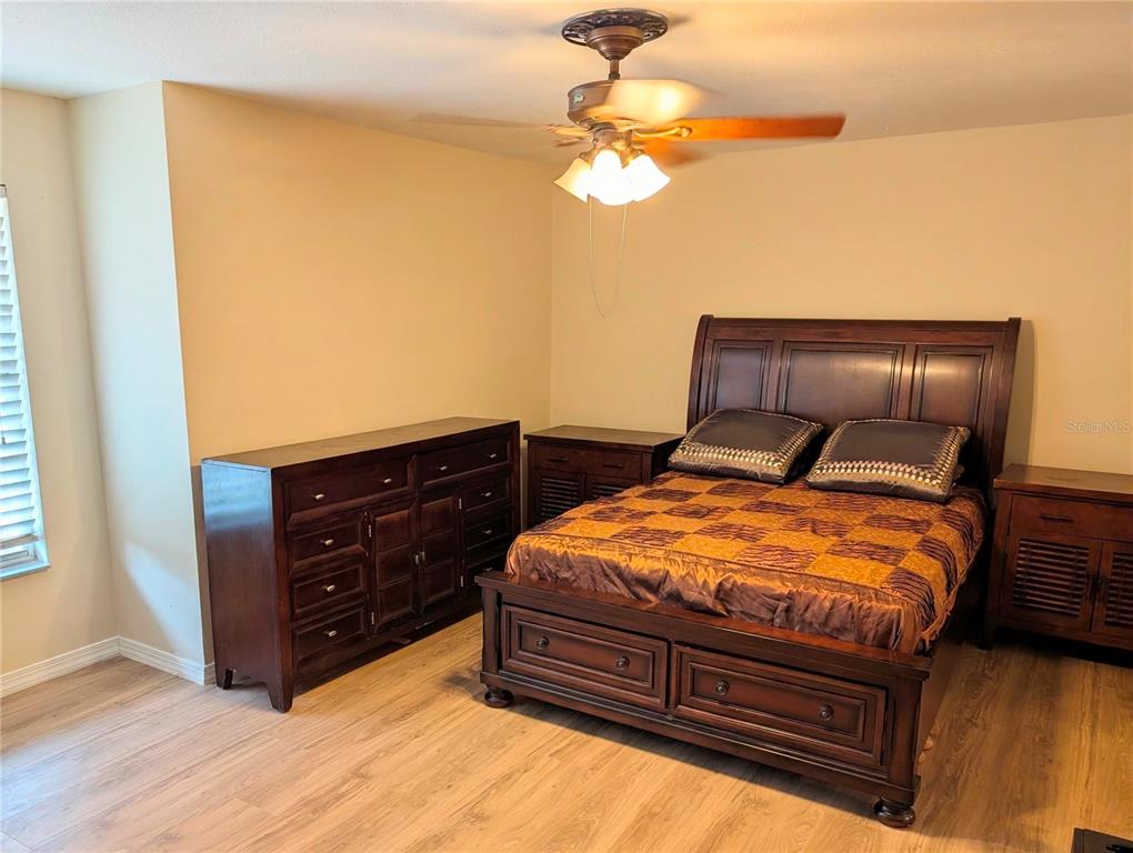 A bedroom features a dark wood bed frame, matching dresser, and light wood-look flooring — 423 WATERFORD WAY, KISSIMMEE, FL