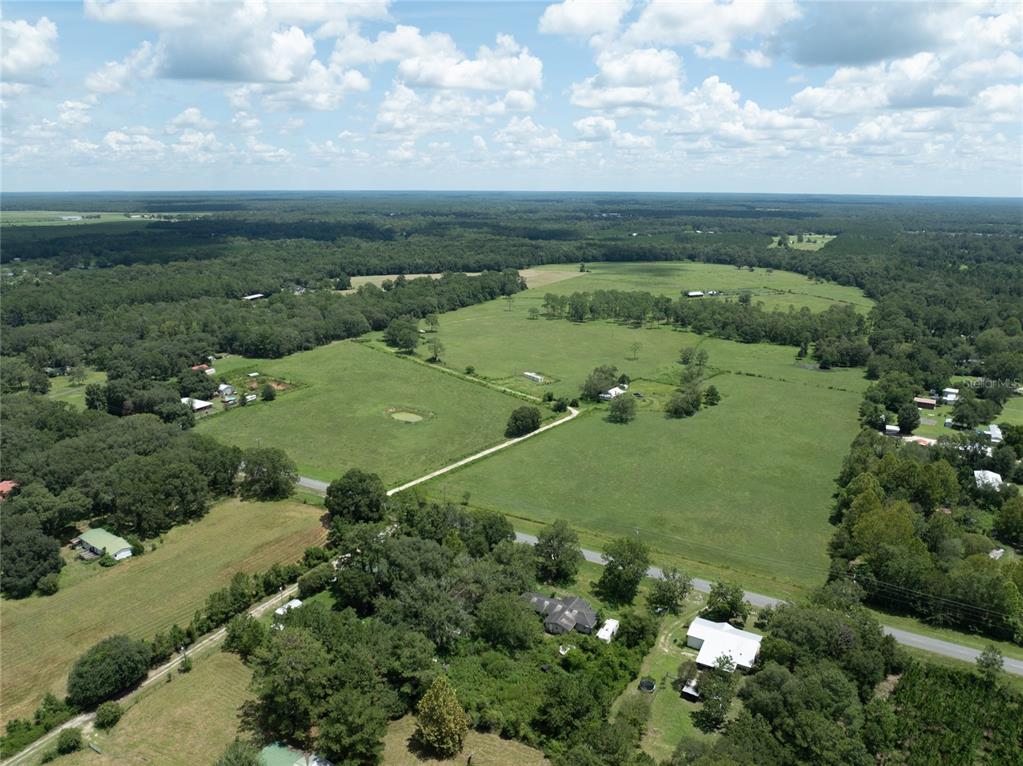 An aerial view shows a large, open green pasture surrounded by dense forest and trees — 0 NW CR 225, STARKE, FL