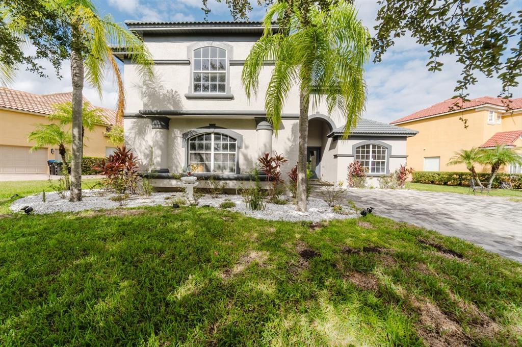 A two-story stucco house with a paved driveway, palm trees, and a landscaped front yard — 1361 WHITNEY ISLES DRIVE, WINDERMERE, FL