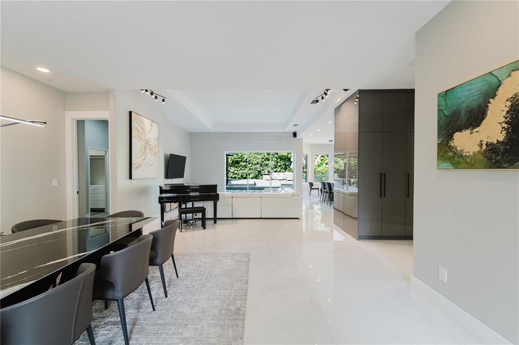 A modern open-concept living and dining area features white tile floors, a piano, and furniture — 1361 WHITNEY ISLES DRIVE, WINDERMERE, FL