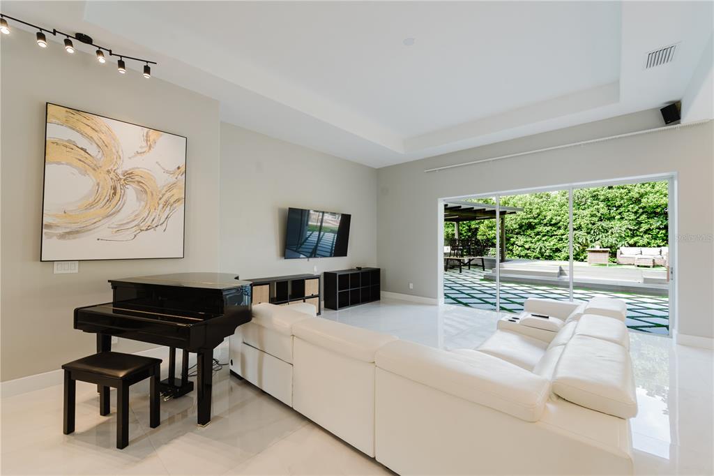 A living room features a white sectional sofa, a black grand piano, and sliding glass doors — 1361 WHITNEY ISLES DRIVE, WINDERMERE, FL