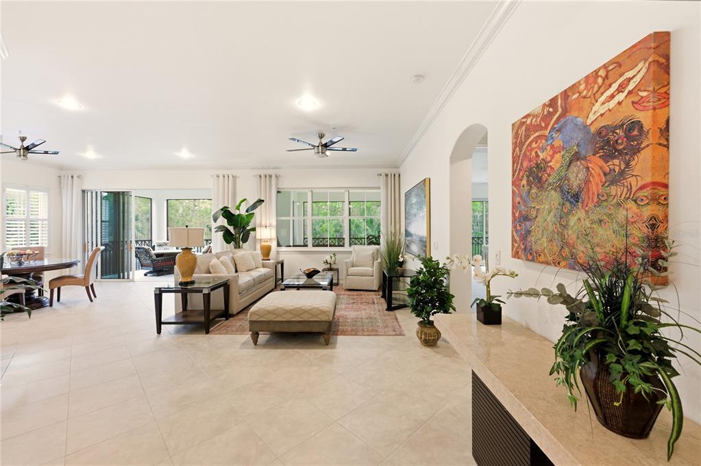 A spacious living room with tile floors, a large area rug, and a colorful wall painting — 2843 TIBURON BOULEVARD E UNIT 7-102, NAPLES, FL