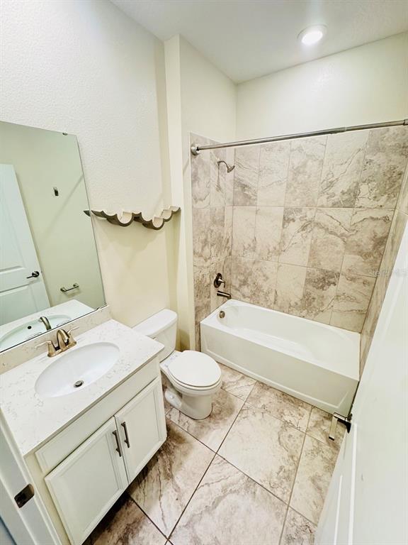 A bathroom features a vanity with a stone countertop, a toilet, and a tiled tub-shower — 1711 LAKE SIMS PARKWAY, OCOEE, FL