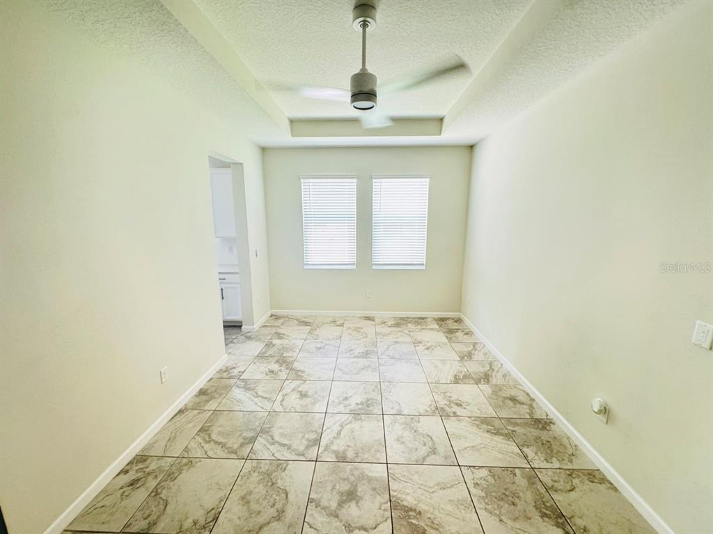 An empty dining room features a tray ceiling with a fan and tiled flooring — 1711 LAKE SIMS PARKWAY, OCOEE, FL