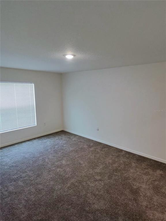 An empty room with beige carpet, white walls, a single window, and a ceiling light — 527 HANSARE STREET SW, PALM BAY, FL