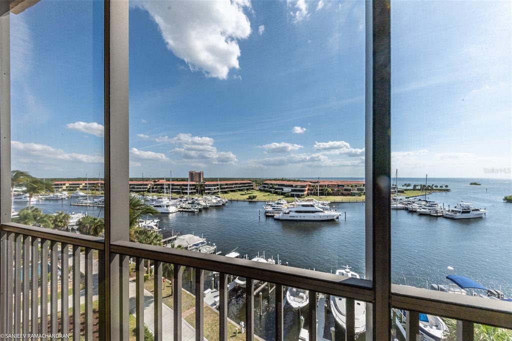 A screened balcony overlooks a marina filled with boats and waterfront residential buildings — 3313 SUNSET KEY CIRCLE UNIT 403, PUNTA GORDA, FL