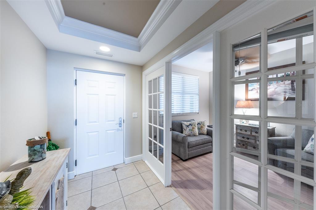 An entryway with tile flooring leads to a room with French doors and wood flooring — 3313 SUNSET KEY CIRCLE UNIT 403, PUNTA GORDA, FL