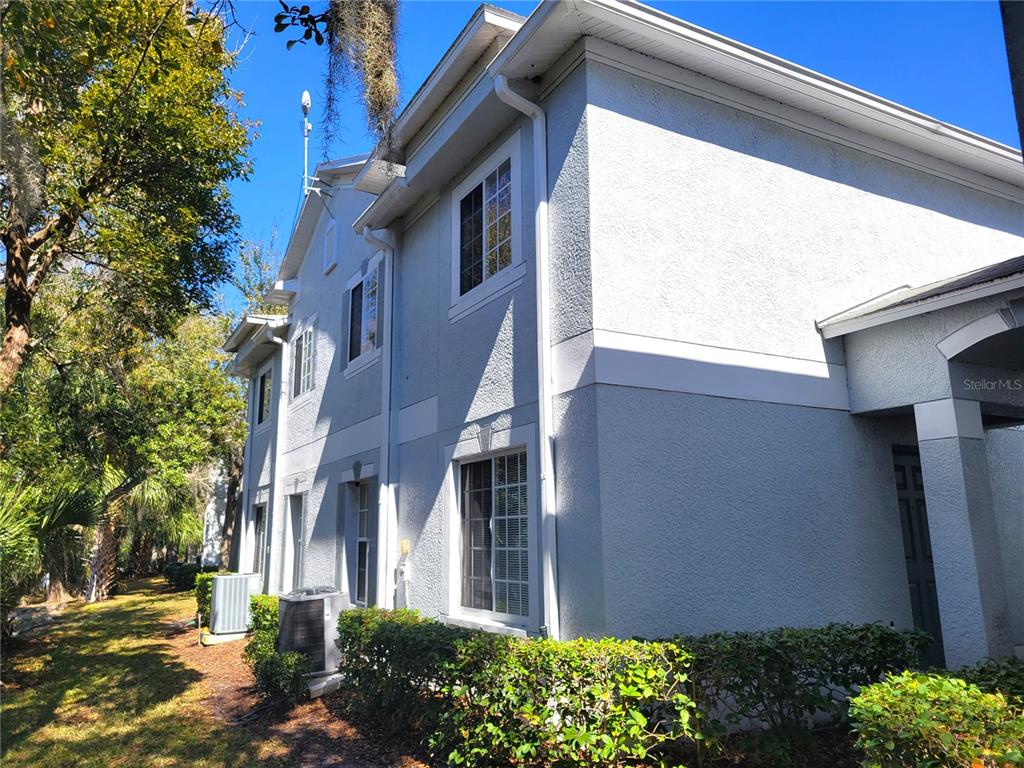 The exterior side view of a two-story stucco building features multiple windows and HVAC units — 4053 DOLPHIN DRIVE, TAMPA, FL