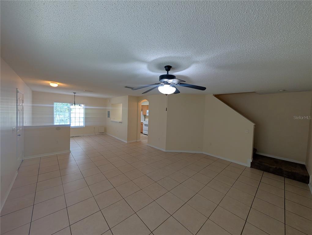 An open-concept living area features light-colored tile flooring, a ceiling fan, and a staircase — 4053 DOLPHIN DRIVE, TAMPA, FL