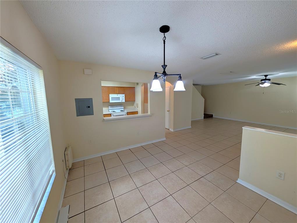 A dining area with tile flooring, a chandelier, and a pass-through window to the kitchen — 4053 DOLPHIN DRIVE, TAMPA, FL