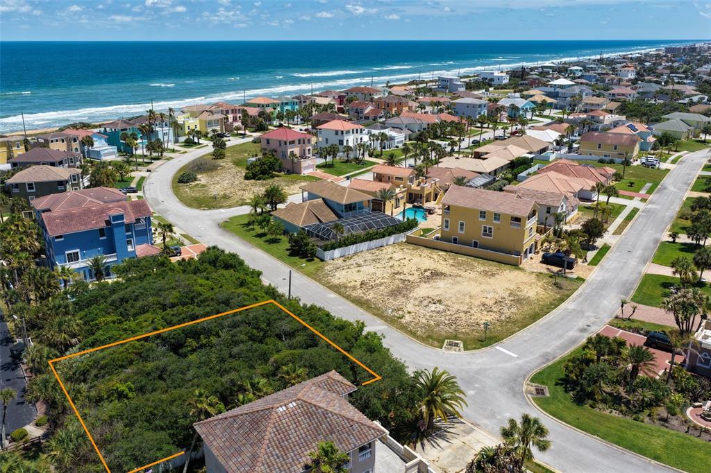 An aerial view shows a vacant, tree-covered residential lot outlined in orange near the ocean — 148 COQUINA KEY DRIVE, ORMOND BEACH, FL