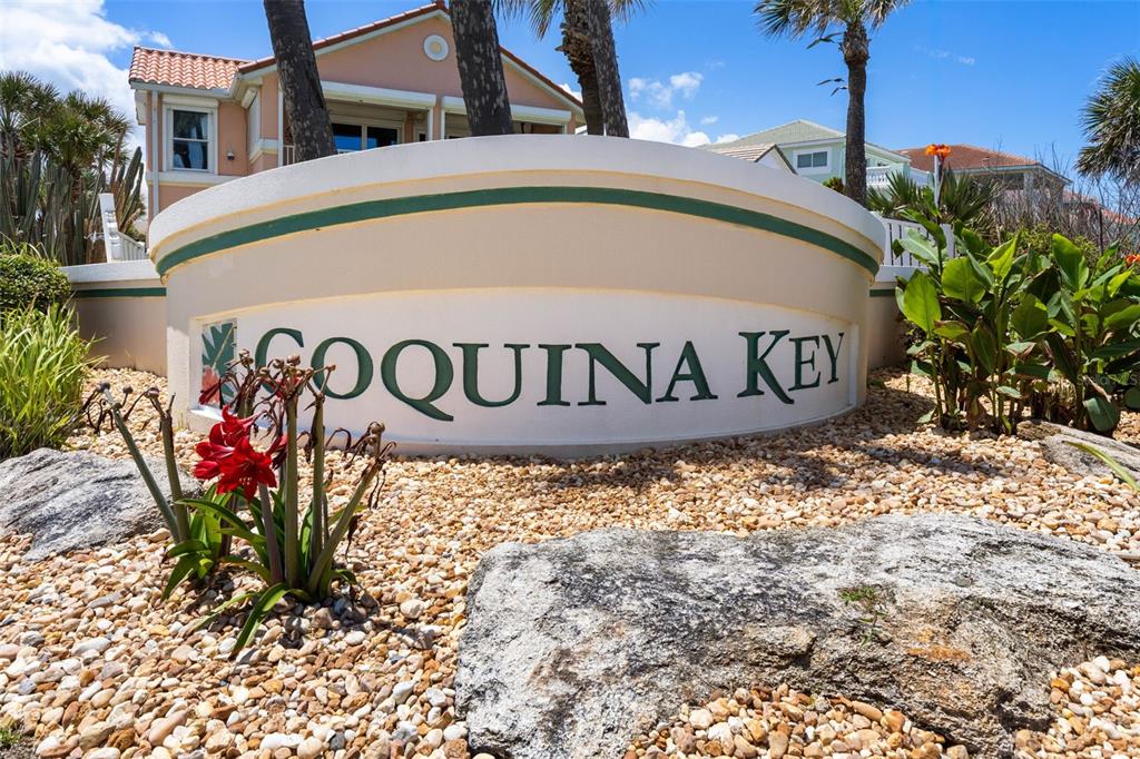 A curved monument sign for Coquina Key stands in front of a residential building — 148 COQUINA KEY DRIVE, ORMOND BEACH, FL