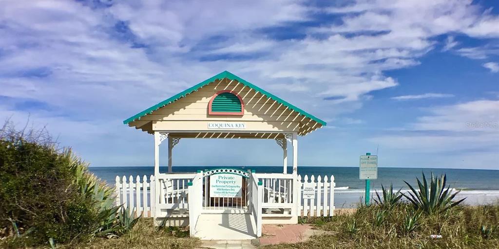 A white wooden gazebo with a green roof sits on a sandy dune overlooking the ocean — 148 COQUINA KEY DRIVE, ORMOND BEACH, FL