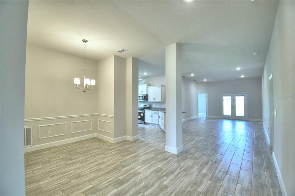 A hallway with light wood-look tile flooring leads toward an open-concept kitchen and living area — 4705 GRANDVIEW GLEN DRIVE, AUBURNDALE, FL
