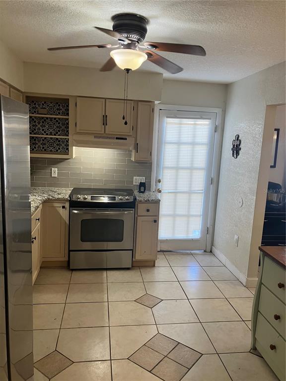 A kitchen features light-colored cabinets, a stainless steel stove, tiled backsplash, and a ceiling fan — 247 DEBORA COURT UNIT 247, ALTAMONTE SPRINGS, FL