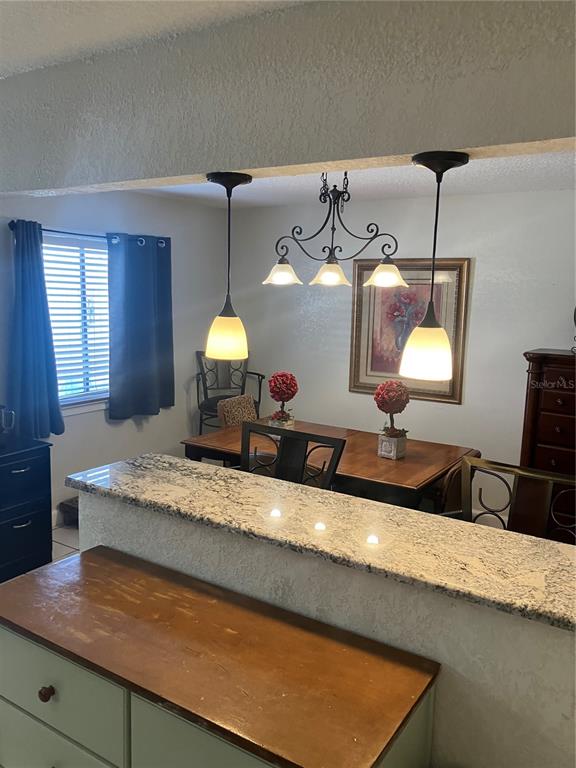 A dining area features a wooden table, a chandelier, and two pendant lights over a counter — 247 DEBORA COURT UNIT 247, ALTAMONTE SPRINGS, FL