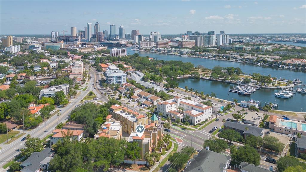 An aerial view shows a multi-story residential complex near a bay with a city skyline — 114 E DAVIS BOULEVARD UNIT 13, TAMPA, FL