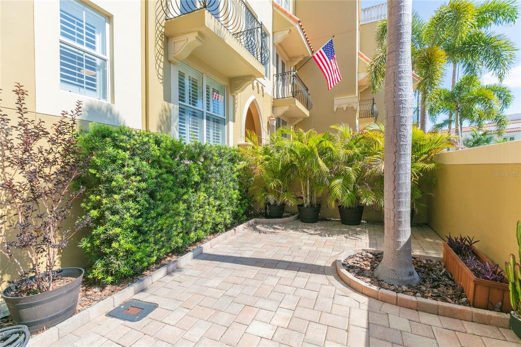 A paved patio area features potted palm plants, a small tree, and a hedge wall — 114 E DAVIS BOULEVARD UNIT 13, TAMPA, FL
