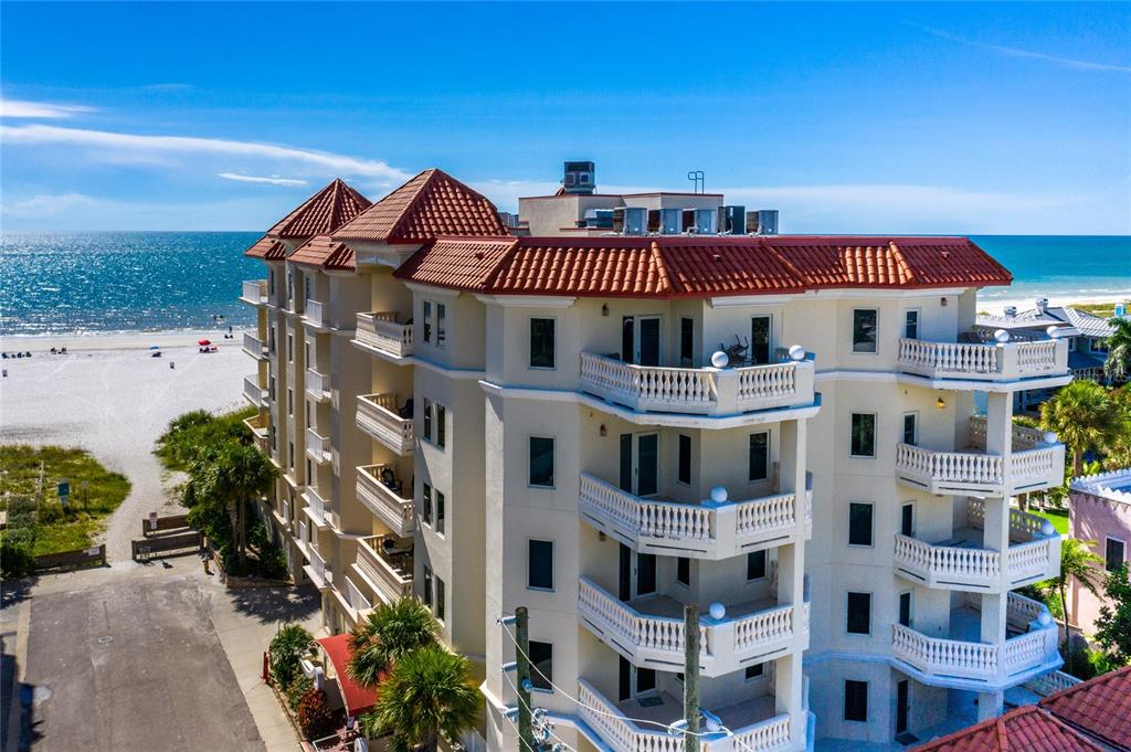 An aerial view of a multi-story beachfront condominium building with balconies and a red-tiled roof — 14 SOMERSET STREET UNIT 5C, CLEARWATER, FL