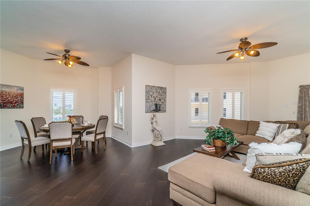 An open-concept living and dining area with dark hardwood floors, ceiling fans, and neutral walls — 14 SOMERSET STREET UNIT 5C, CLEARWATER, FL