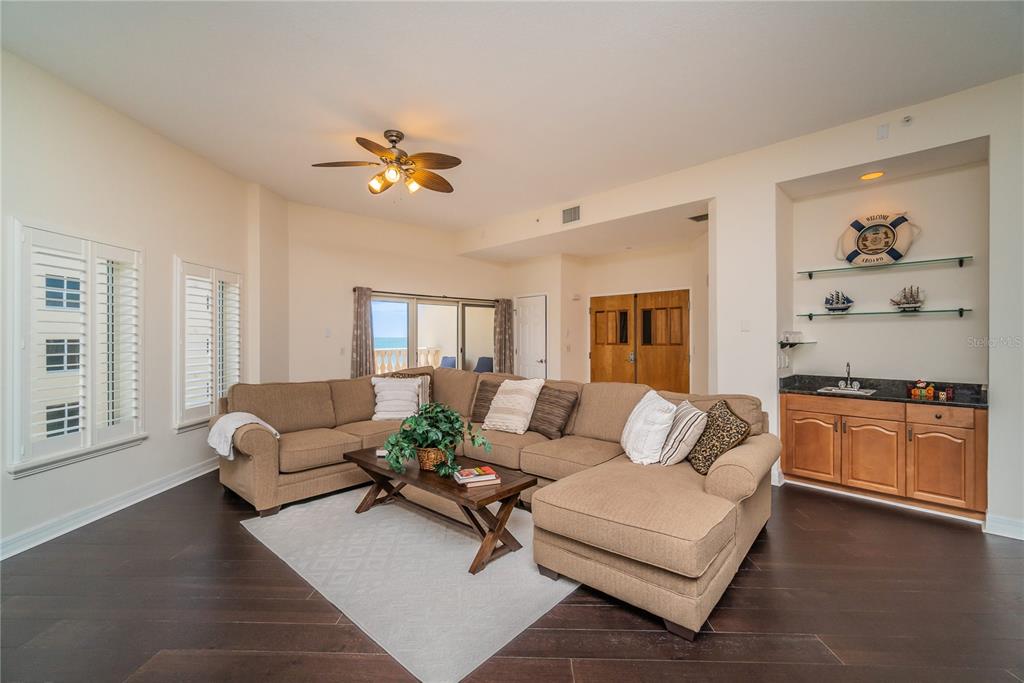 A living room features a large tan sectional sofa, dark wood floors, and a wet bar — 14 SOMERSET STREET UNIT 5C, CLEARWATER, FL