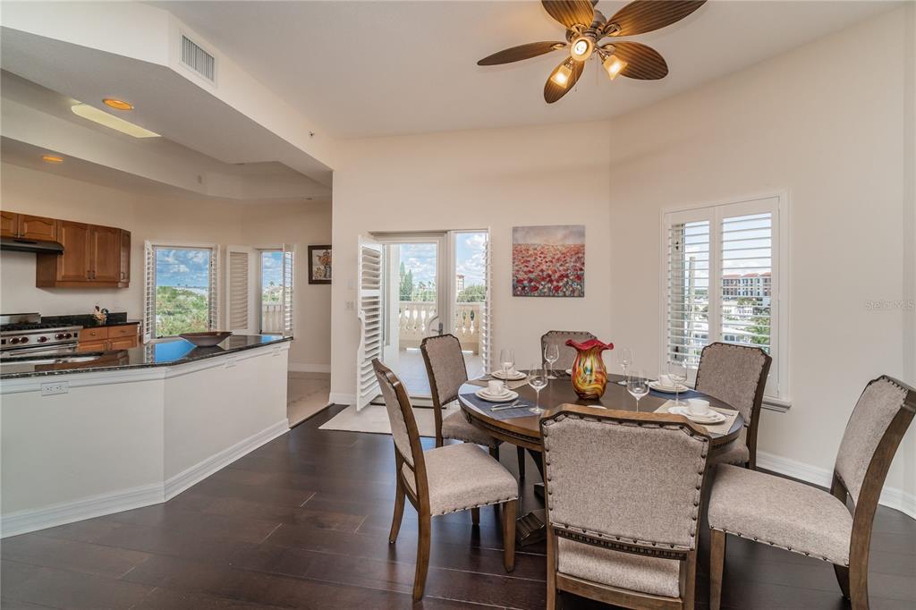 A dining area with a round table, upholstered chairs, dark wood floors, and balcony access — 14 SOMERSET STREET UNIT 5C, CLEARWATER, FL