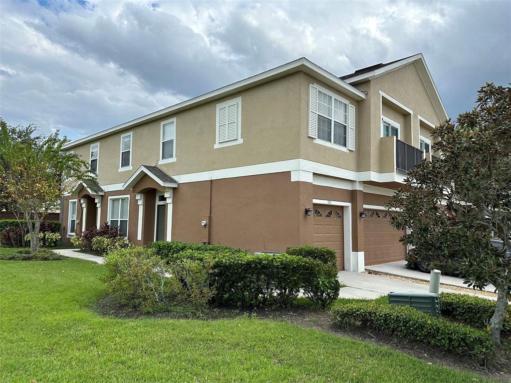 A two-story townhouse with a tan and brown exterior, two garages, and a small balcony — 1903 ESTANCIA CIRCLE UNIT 1903, KISSIMMEE, FL