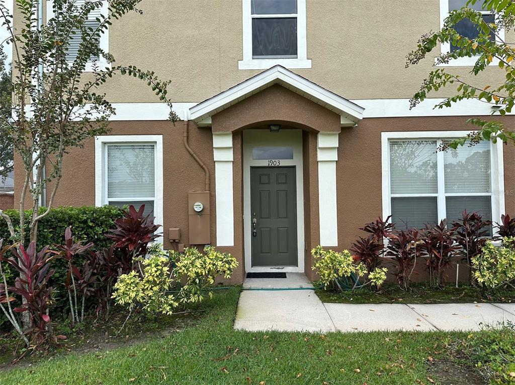 A two-story townhouse exterior features a dark green front door under a small covered porch — 1903 ESTANCIA CIRCLE UNIT 1903, KISSIMMEE, FL