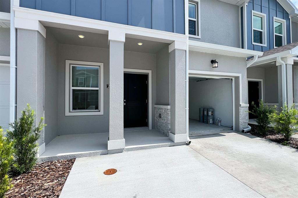 The exterior of a two-story townhouse features a covered entryway, a garage, and stone accents — 2607 SKYLINE LOOP, KISSIMMEE, FL