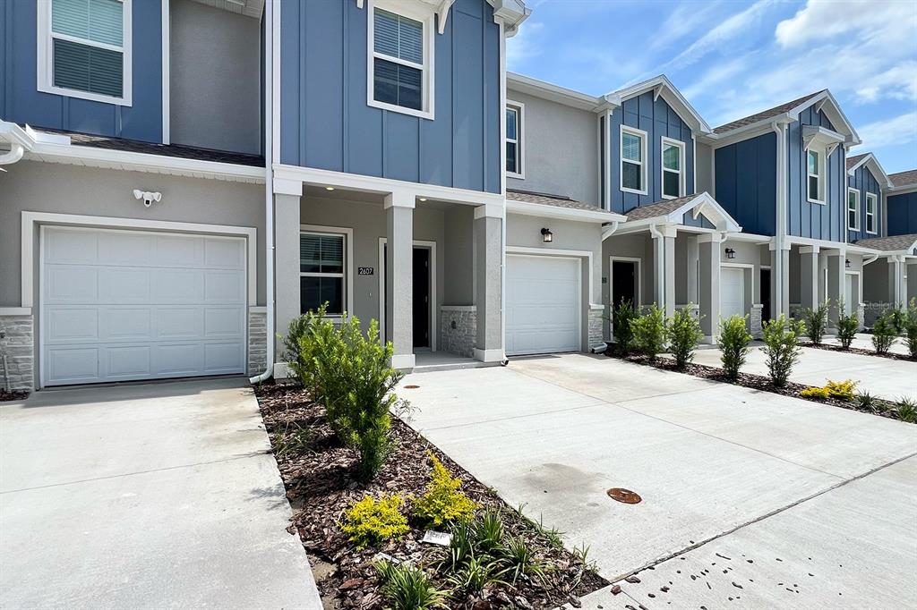 A row of modern townhomes with blue siding, gray stucco, and attached single-car garages — 2607 SKYLINE LOOP, KISSIMMEE, FL