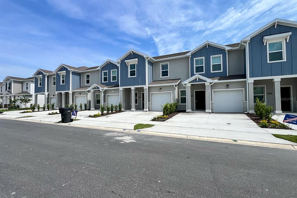 A row of modern two-story townhouses with blue and gray siding and attached garages — 2607 SKYLINE LOOP, KISSIMMEE, FL