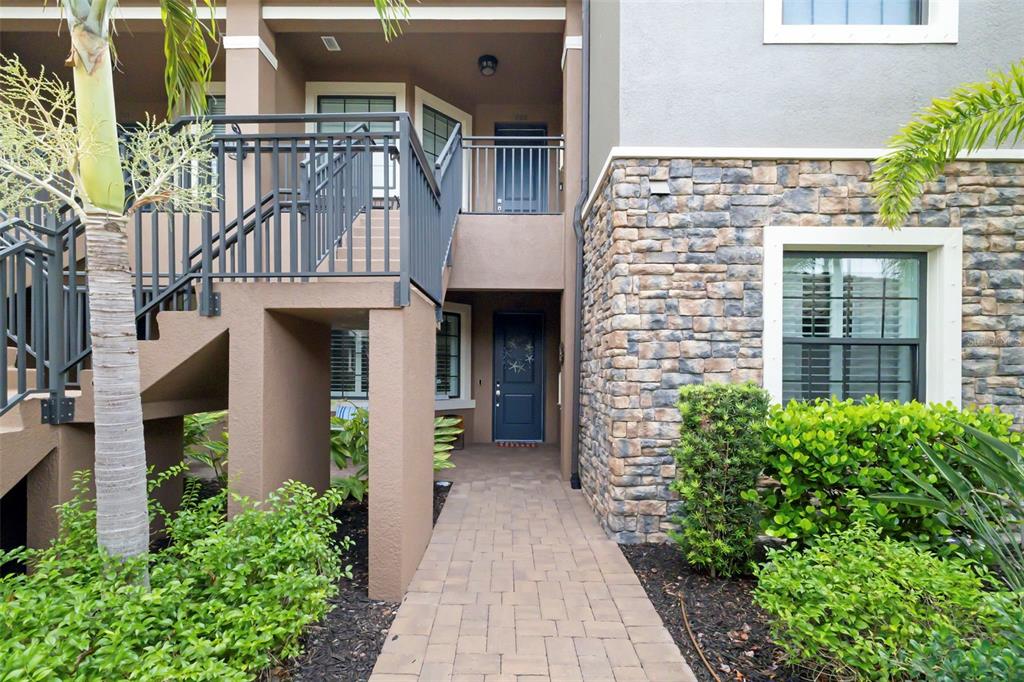 A paved walkway leads to the dark blue front door of a multi-story building — 13828 MESSINA LOOP UNIT 102, BRADENTON, FL