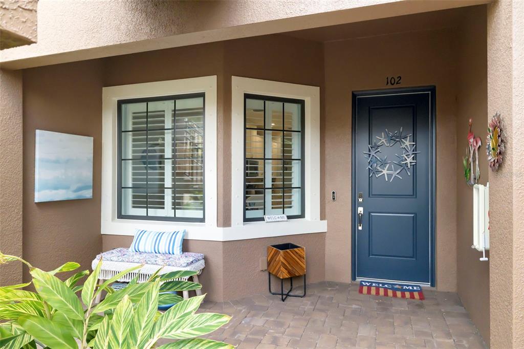 A front porch with a blue door, a bench, and a window with black shutters — 13828 MESSINA LOOP UNIT 102, BRADENTON, FL