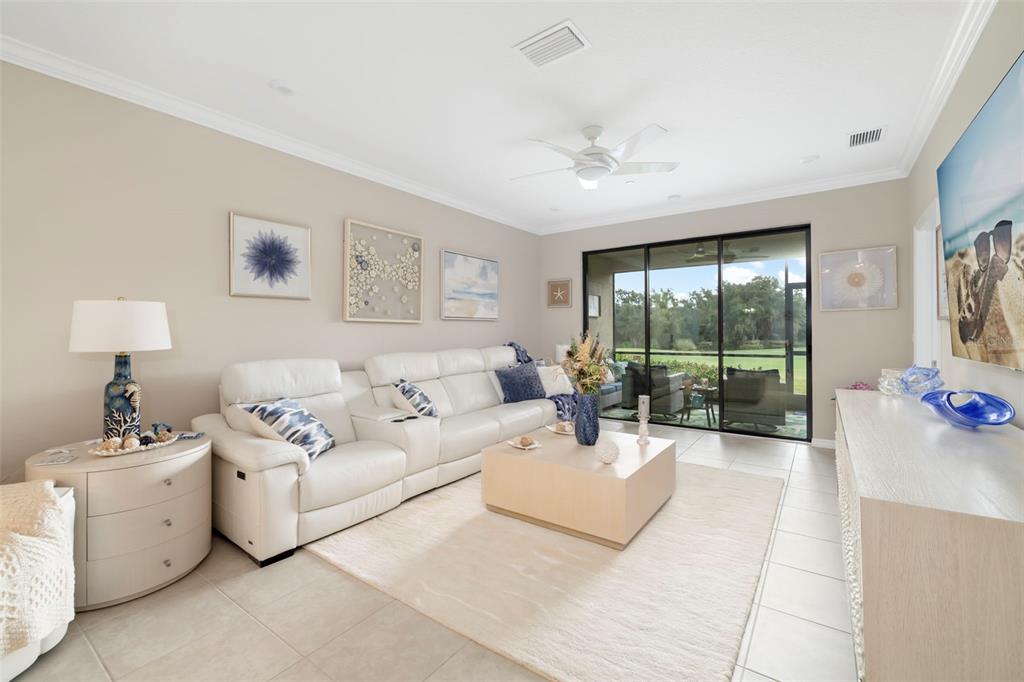 A bright living room features a white leather sofa, a coffee table, and sliding glass doors — 13828 MESSINA LOOP UNIT 102, BRADENTON, FL