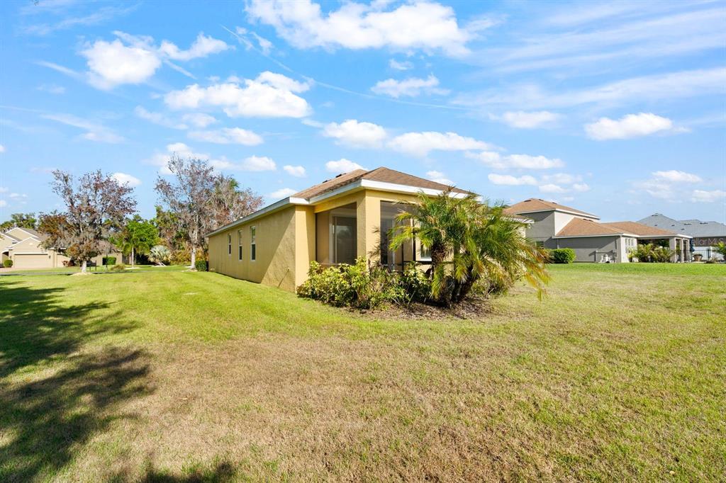 A yellow house with a screened-in porch sits on a large, grassy residential lot — 5515 74TH PLACE E, ELLENTON, FL