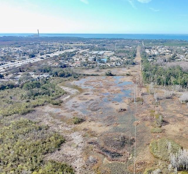 An aerial view shows a large, marshy, undeveloped lot with power lines and distant housing — NO ADDRESS ASSIGNED, HOLIDAY, FL