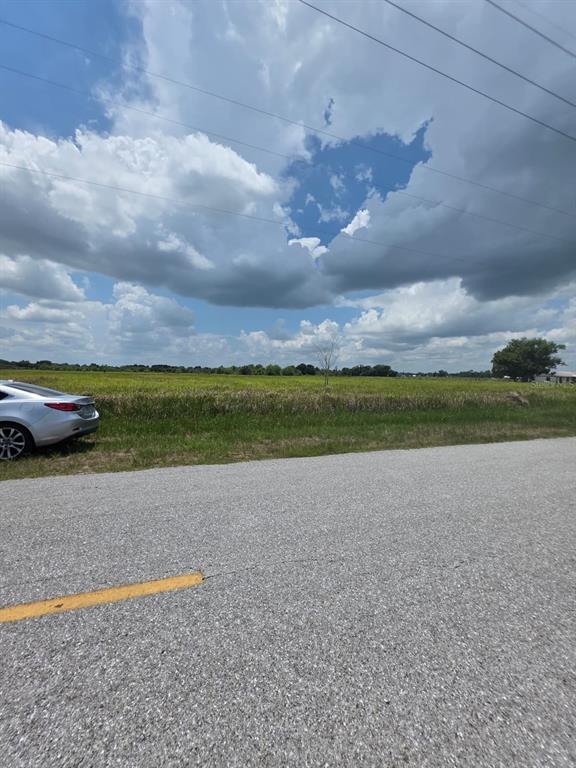 A silver car is parked on the shoulder next to a large, open grassy field — METHENY RD, PARCEL C, WAUCHULA, FL
