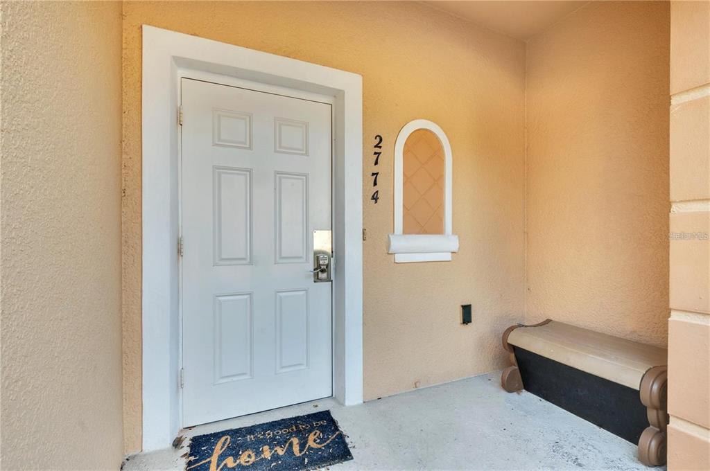 A white front door with a house number and a bench on a covered porch — 2774 CORVETTE LANE, KISSIMMEE, FL