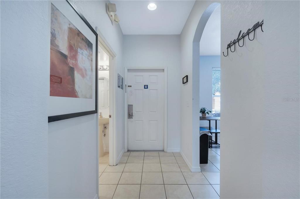 An entryway with tiled floors leads to a white front door and an adjacent bathroom — 2774 CORVETTE LANE, KISSIMMEE, FL
