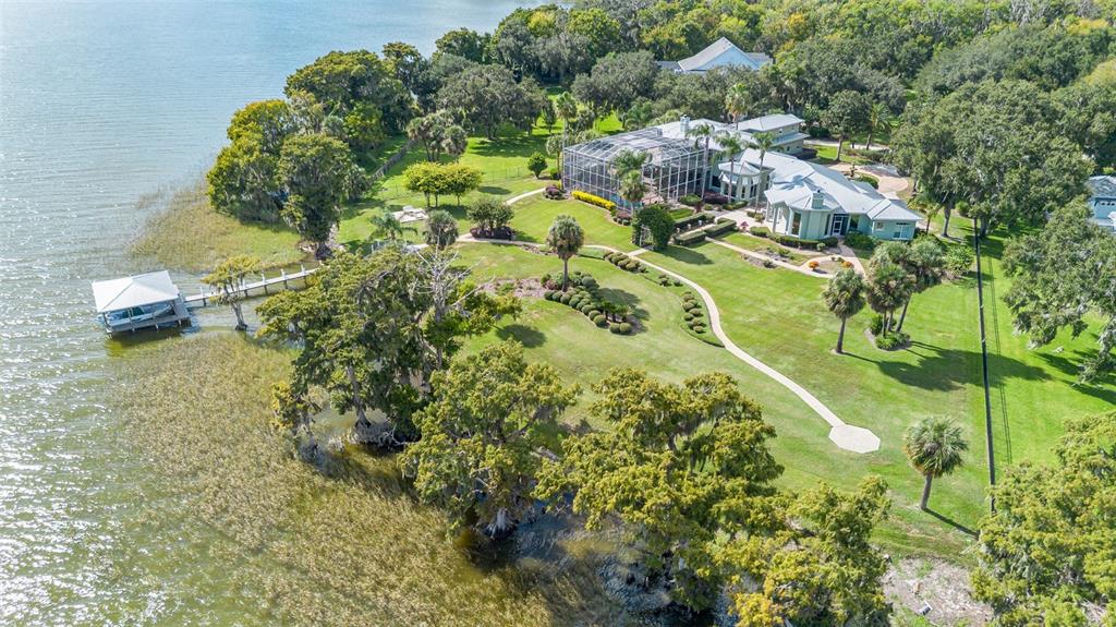 An aerial view shows a waterfront house with a screened pool enclosure and private dock — 30215 REDTREE DRIVE, LEESBURG, FL
