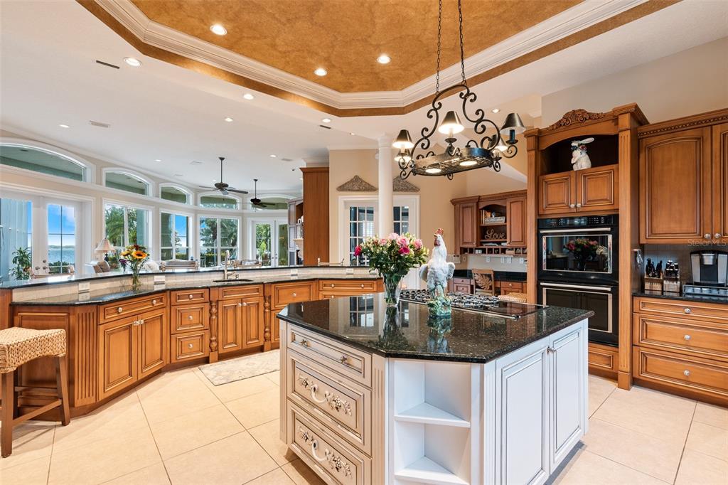 A kitchen features wood cabinetry, a central white island with a dark countertop, and tile flooring — 30215 REDTREE DRIVE, LEESBURG, FL